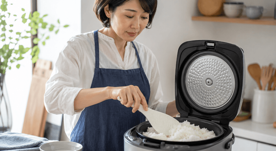 朝日米の粒立ちを整えるため炊飯後のごはんをしゃもじでほぐす日本人女性