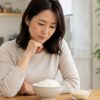 朝日米の味や硬さを心配しながら炊いた白ごはんを見る日本人女性