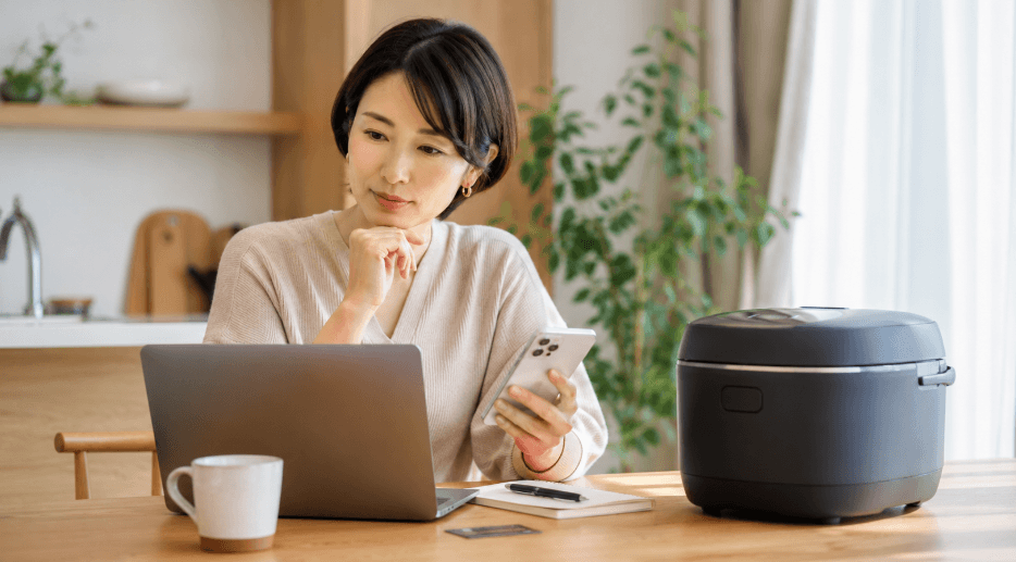 日立ふっくら御膳の価格をパソコンとスマートフォンで比較する女性