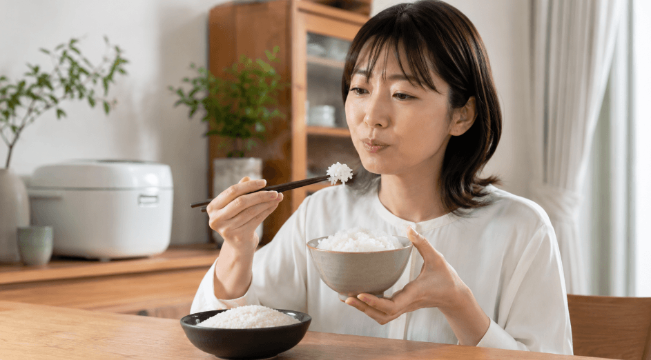 さんさんまる米の味や食感を確かめるために、炊きたてのご飯を箸で食べ比べる日本人女性