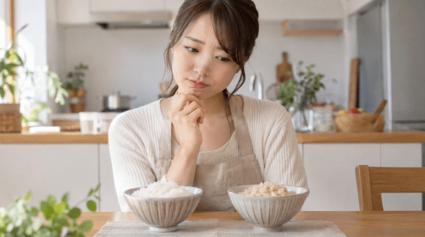 白米と玄米を見比べながら玄米がまずいか考える女性