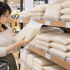 スーパーの米売り場で袋入りのお米を手に取り、商品を比較する女性