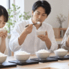 複数の白ごはんを食べ比べて香りや味を確かめる日本人の男女3人